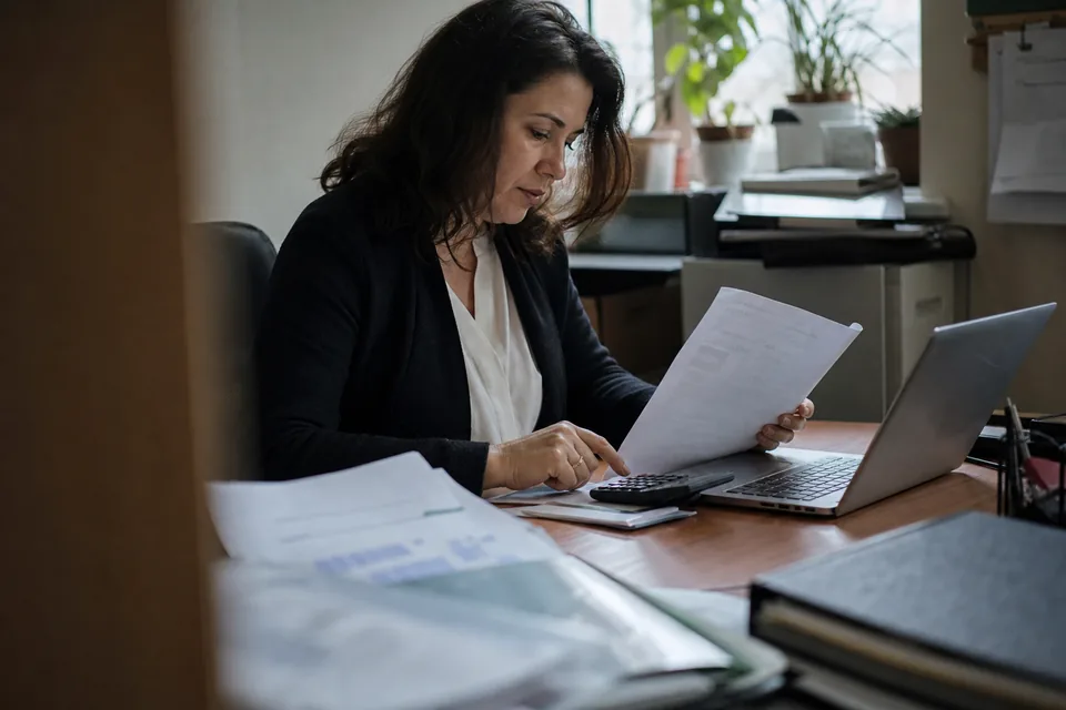 Dyrektorka finansowa sprawdza koszt rocznej subskrypcji narzędzia na laptopie, obok kalkulator